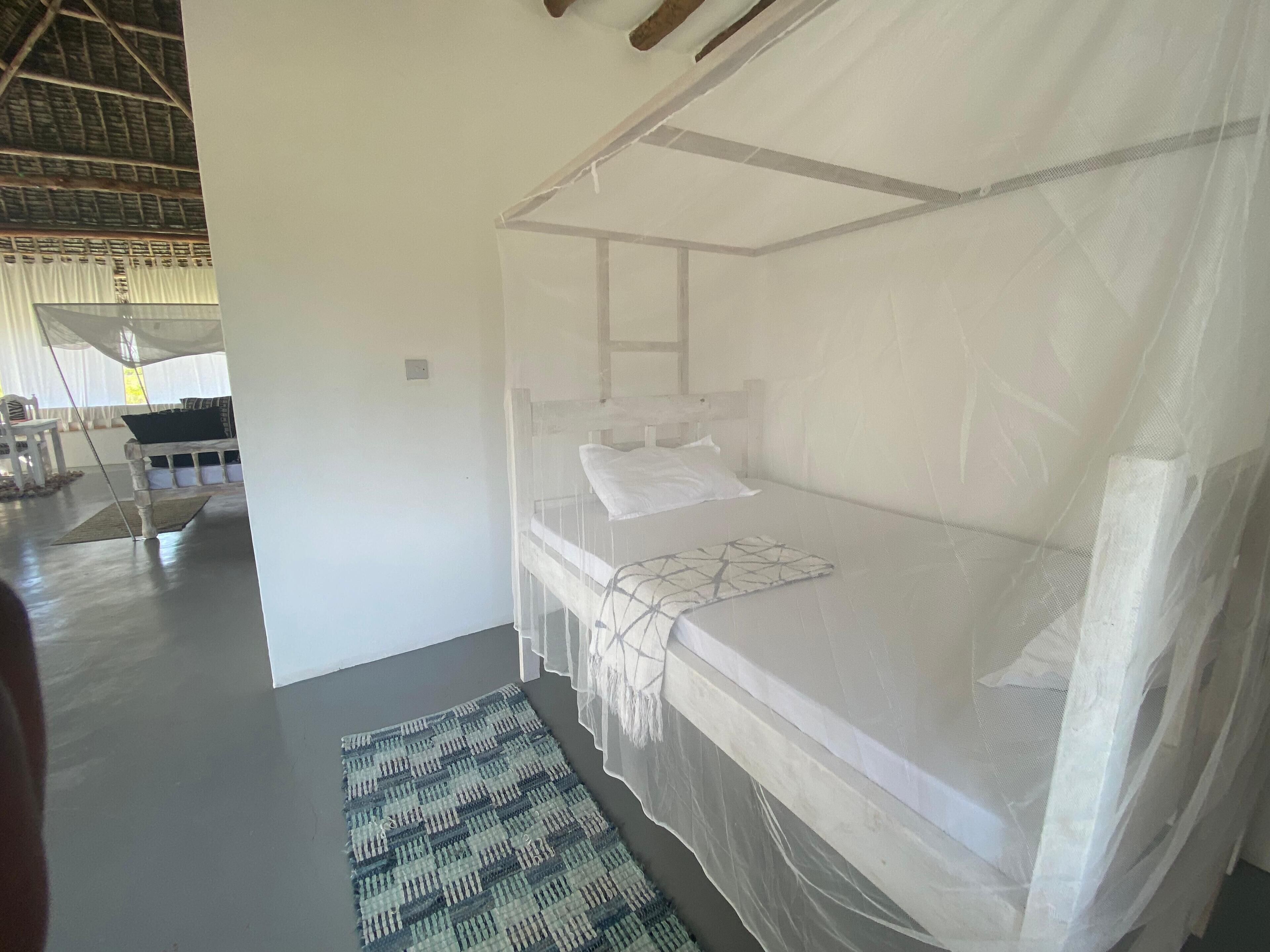 A single bed with a canopy, a small bedside table, and a patterned rug.