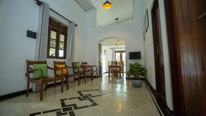 A hallway with wooden chairs, a patterned floor, a potted plant, and a door. - Sleeperwood Villa (Unawatuna)