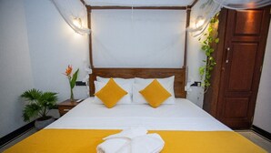 A neatly made bed with white and yellow bedding, a wooden headboard, and a yellow accent pillow. - Sleeperwood Villa (Unawatuna)