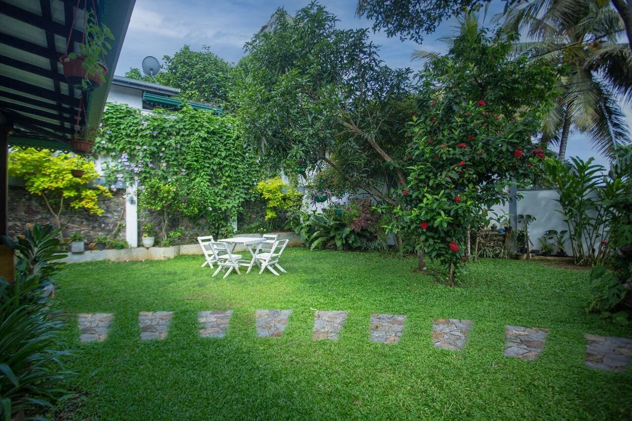 A well-maintained garden with a stone pathway leading to a table and chairs.