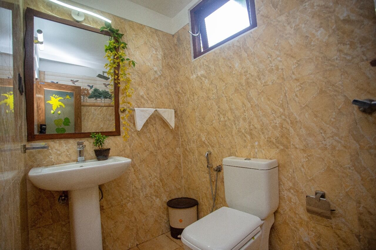A bathroom with a marble wall, a sink, a toilet, and a window.