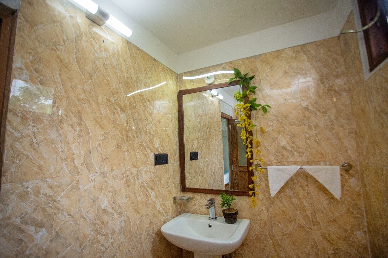 Une salle de bain avec un mur en marbre, un lavabo, un miroir et un porte-serviettes.