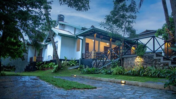 A traditional-style building with a stone staircase, a covered porch, and a well-maintained garden. - Sleeperwood Villa (Unawatuna)