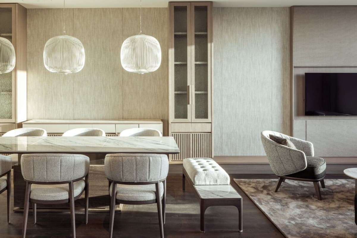 A modern dining area with a marble table, upholstered chairs, a bench, and pendant lights.