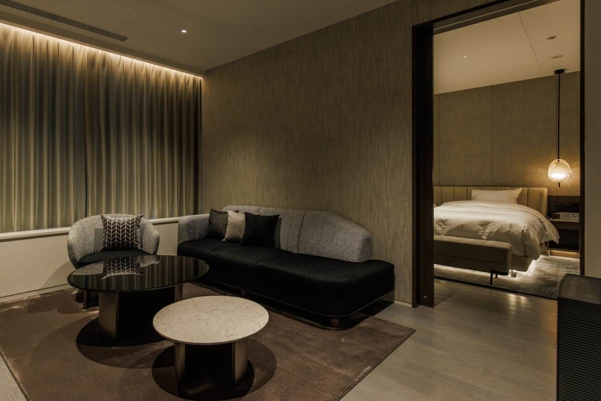 A modern hotel room with a sofa, a coffee table, a round table, and a bed.