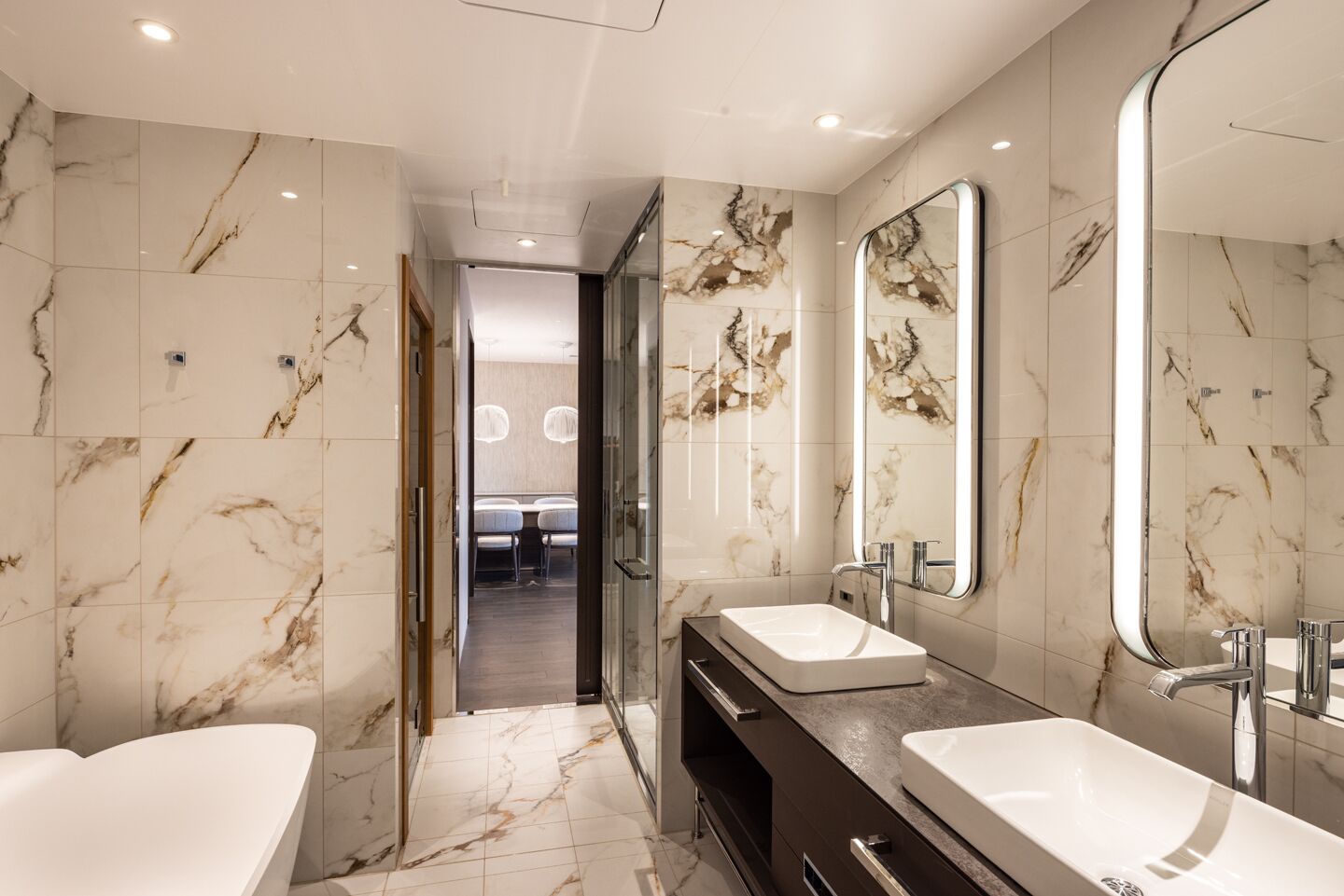 A modern bathroom with marble walls, two sinks, and a vanity.