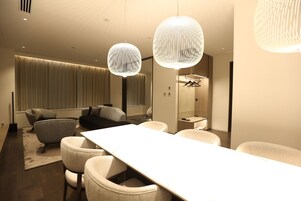 Una habitación de hotel moderna con una larga mesa de comedor, asientos cómodos e iluminación colgante elegante.