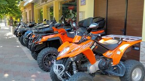 A row of orange quad bikes parked outside a building with a yellow facade and a sign that reads "MOTO ACQUA". - B&B the bikers (Guspini)