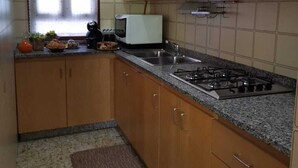 A kitchen with wooden cabinets, a gas stove, a microwave, and a window with curtains. - B&B the bikers (Guspini)