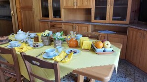 A dining table set with tea service, fruit, and flowers, surrounded by wooden cabinets. - B&B the bikers (Guspini)