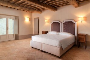 Ein Schlafzimmer mit einem großen Bett, einem Holzkopfteil, zwei Nachttischen und einer Tür mit Glasfeldern.