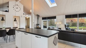 A modern kitchen with a large island, white cabinetry, and a skylight.