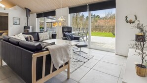 A modern living room with a sofa, chairs, a dining table, and a fireplace.