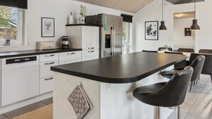 A modern kitchen with white cabinetry, a black countertop, and a central island with bar stools.