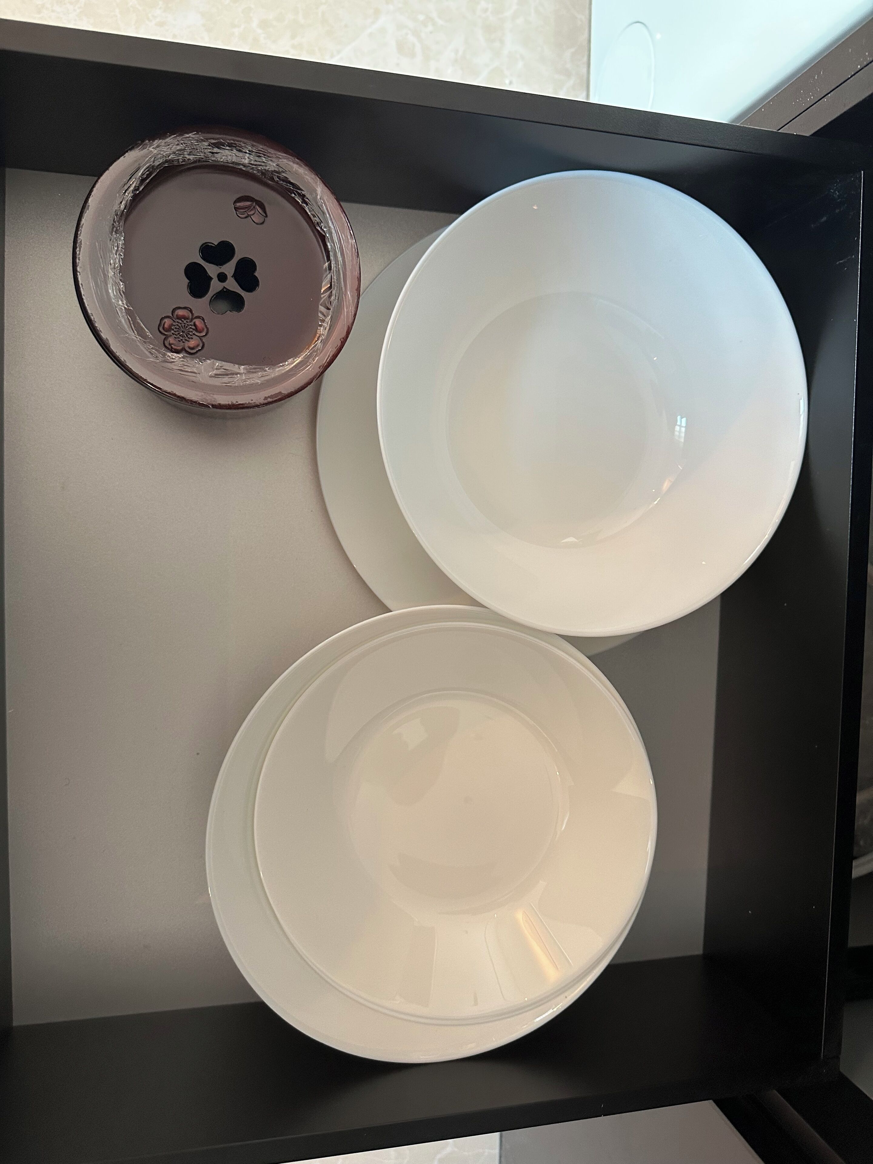 A black tray with three white plates, one with a floral design.