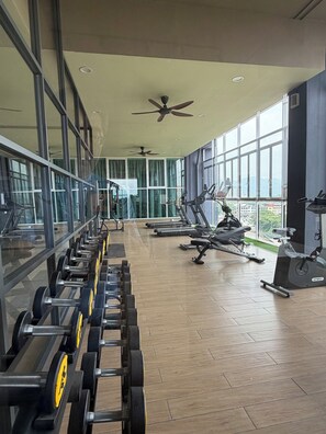 A gym with exercise equipment, large windows, and a ceiling fan. - ICC Luxury Suites Ipoh City Centre (Ipoh)