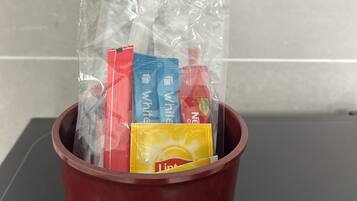 A brown bucket containing various toiletries, including a yellow bottle labeled 'Lindt' and several packets of 'White' and 'Red' products.