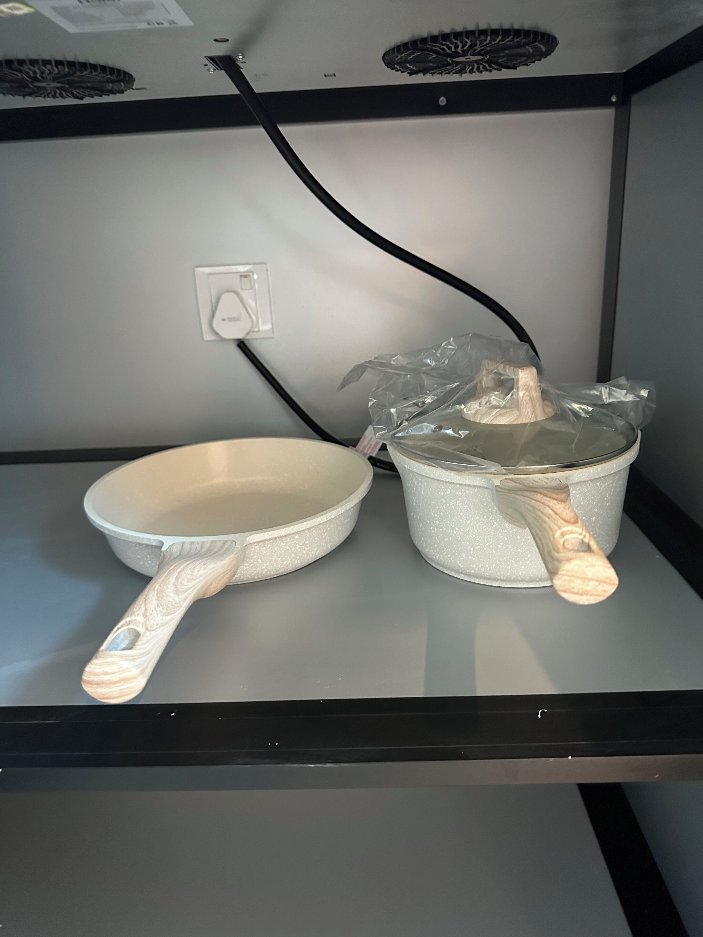 A kitchen with a white frying pan and a white saucepan on a countertop.