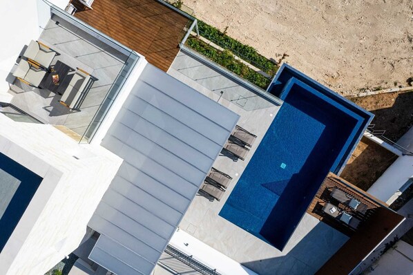 A modern building with a swimming pool, outdoor seating, and a landscaped area.