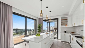 A modern kitchen with a central island, white cabinetry, and pendant lighting.