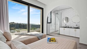 A bedroom with two beds, a large window, and a view of a cityscape.