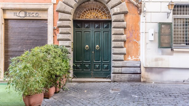 A green double door with a decorative arch above it, flanked by potted plants. - Casa Iside in Rome With 1 Bedrooms and 1 Bathrooms (Rome)