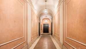 A hallway with a herringbone floor, cream-colored walls, and a black door at the end. - Casa Iside in Rome With 1 Bedrooms and 1 Bathrooms (Rome)