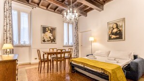 A bedroom with a bed, a chandelier, a table with chairs, and two paintings on the wall. - Casa Iside in Rome With 1 Bedrooms and 1 Bathrooms (Rome)