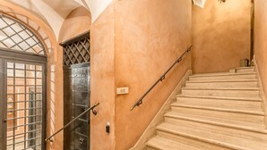 A staircase with a handrail, a door with a metal grille, and a wall with a textured finish. - Casa Iside in Rome With 1 Bedrooms and 1 Bathrooms (Rome)
