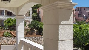 A covered outdoor area with stone columns and a view of surrounding buildings. - Antique apartment with balcony (Stari Grad)