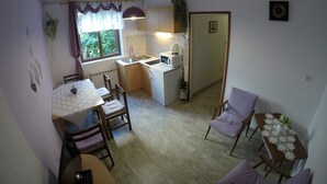 A compact kitchen with a dining area, featuring a table, chairs, a small refrigerator, and a window with curtains. - Antique apartment with balcony (Stari Grad)
