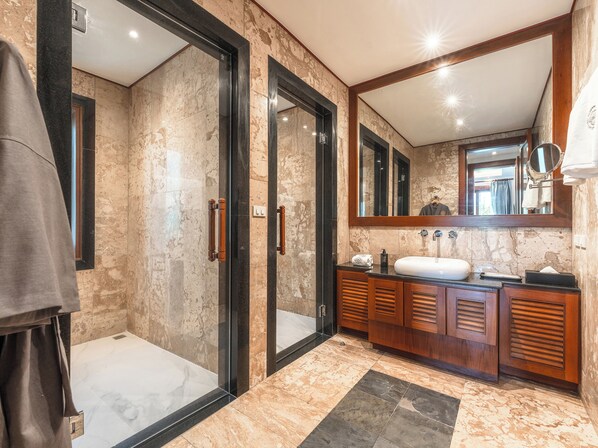 A modern bathroom with a glass-enclosed shower, a large mirror, and wooden cabinetry.