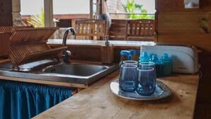 Een keuken met een spoelbak, houten stoelen, een broodrooster en een dienblad met glazen.