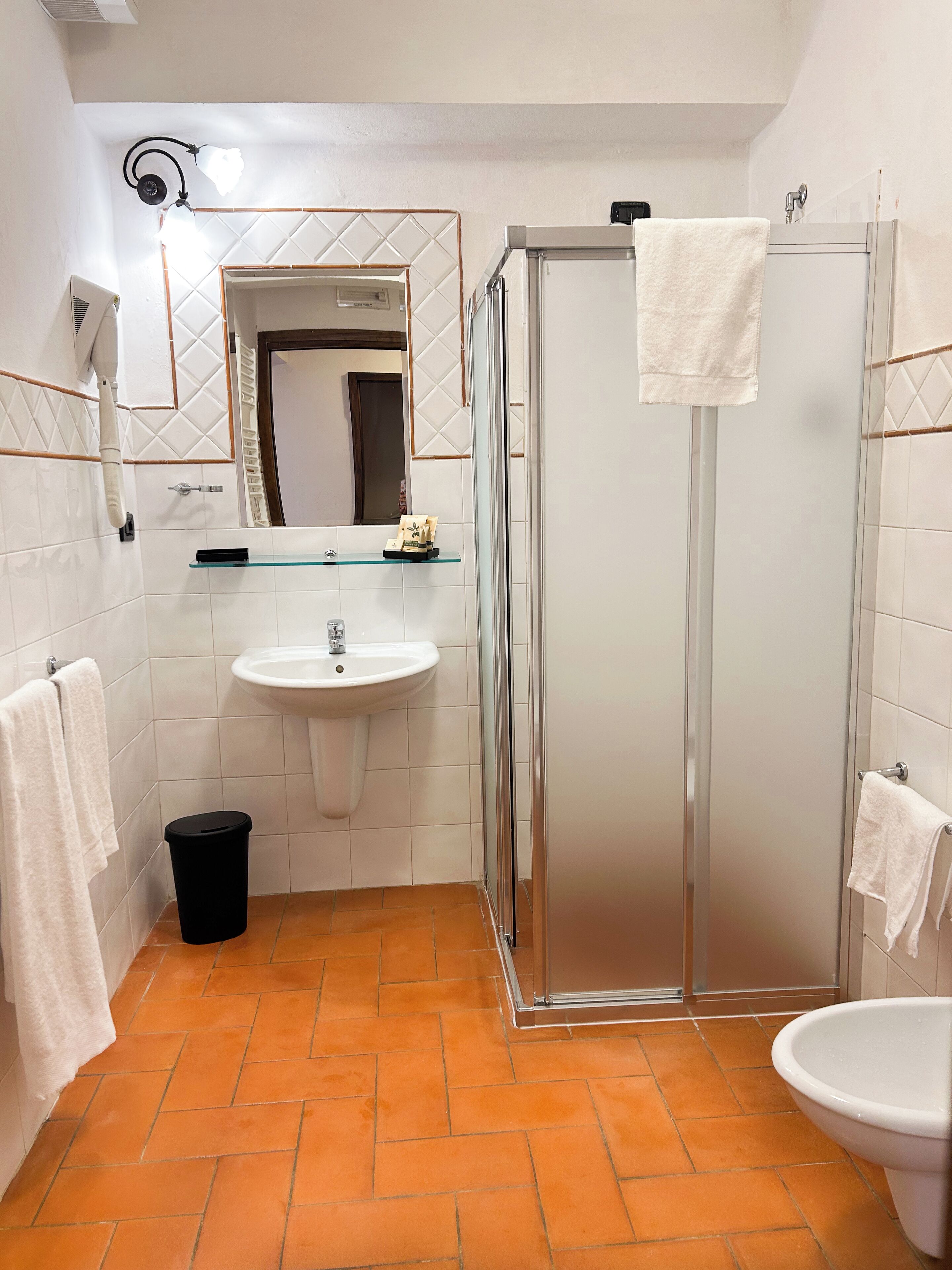Un baño con un lavamanos blanco, un box de ducha de vidrio y un inodoro.