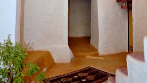 A narrow corridor with a rustic stone archway, a small window with a clay pot, and a wooden door. - DAR INFIANE Tata  (Tigzmerte)