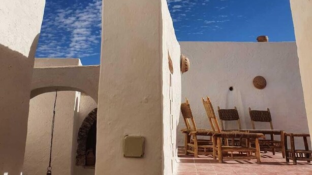 A courtyard with white walls, a wooden chair, and a hanging lantern. - DAR INFIANE Tata  (Tigzmerte)