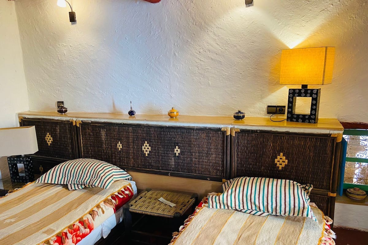 A room with two beds, a small table, and a lamp.