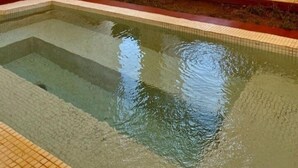 A swimming pool with clear water, surrounded by white walls and a red border. There are two windows with views of a desert landscape. - DAR INFIANE Tata  (Tigzmerte)