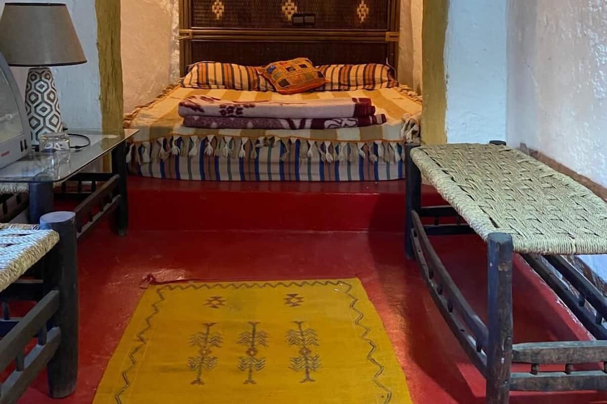 A small, cozy room with a bed, a table, and a chair.