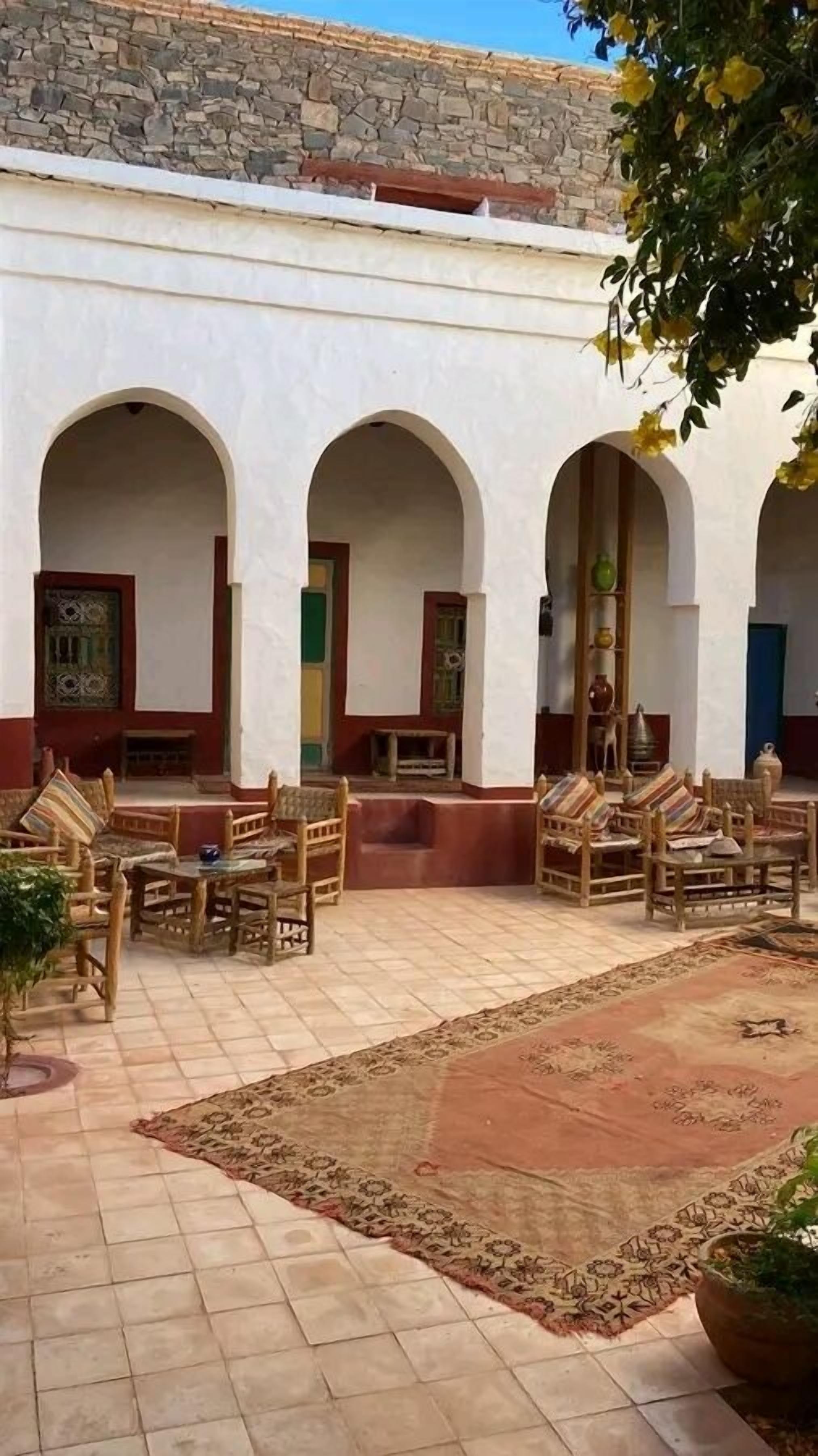 A courtyard with arches, tiled flooring, and wooden furniture.