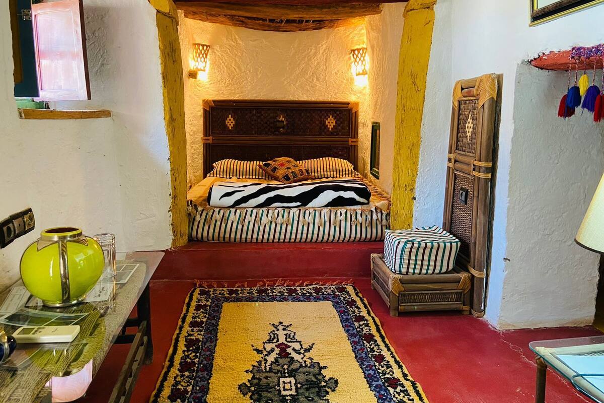 A cozy bedroom with a bed, a small table, and a chair.
