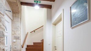 A hallway with a wooden staircase, stone walls, and a white door. - Stephane City Vibe Suites (Trogir)