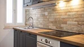 A kitchen with grey cabinets, a wooden countertop, a stainless steel sink, and a built-in oven. - Stephane City Vibe Suites (Trogir)