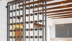 A room with a partition featuring a floral pattern, a kitchen area with grey cabinets, and a wooden ceiling beam. - Stephane City Vibe Suites (Trogir)