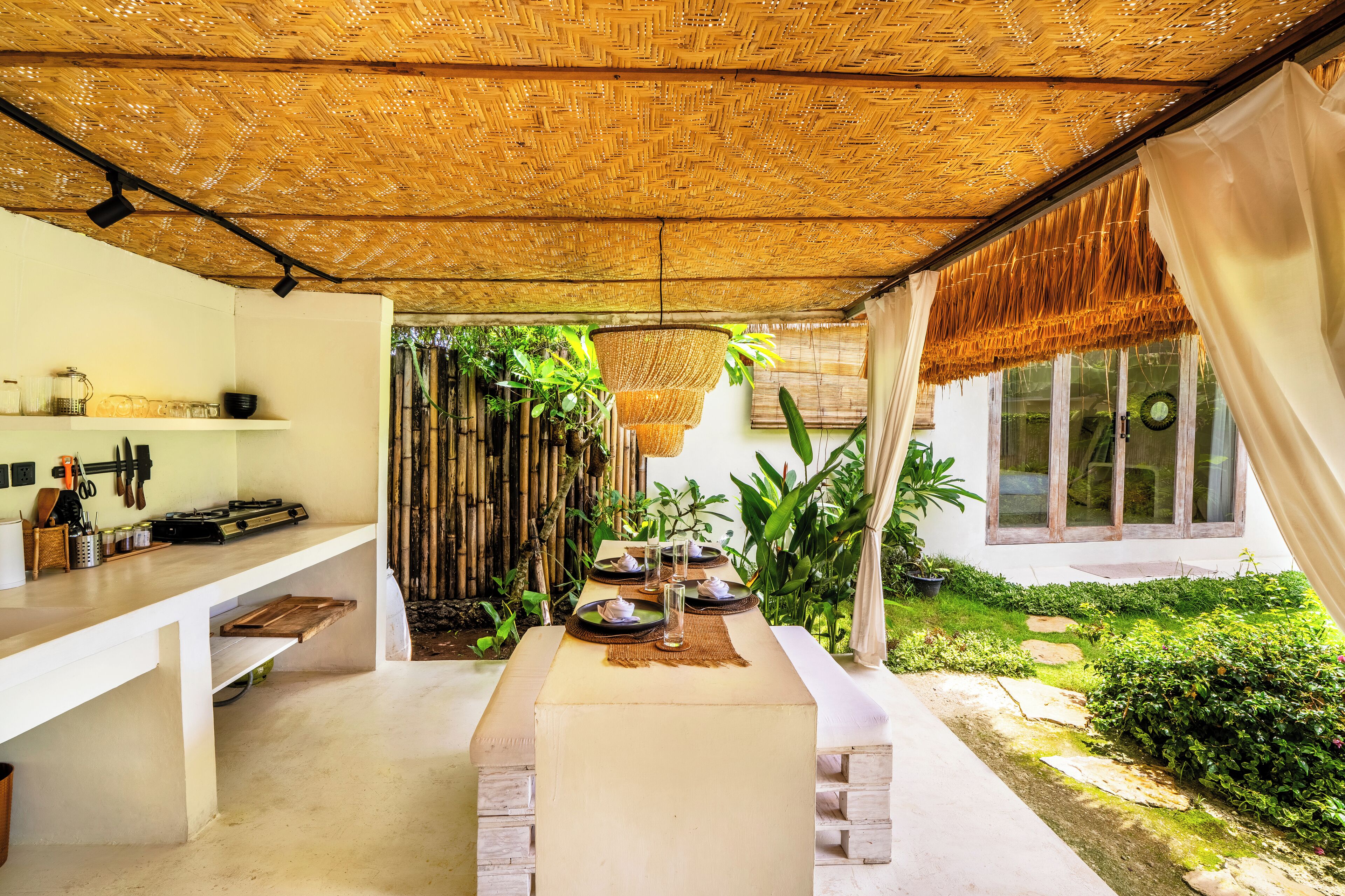 A dining area with a thatched roof, a buffet table, and a view of a garden.