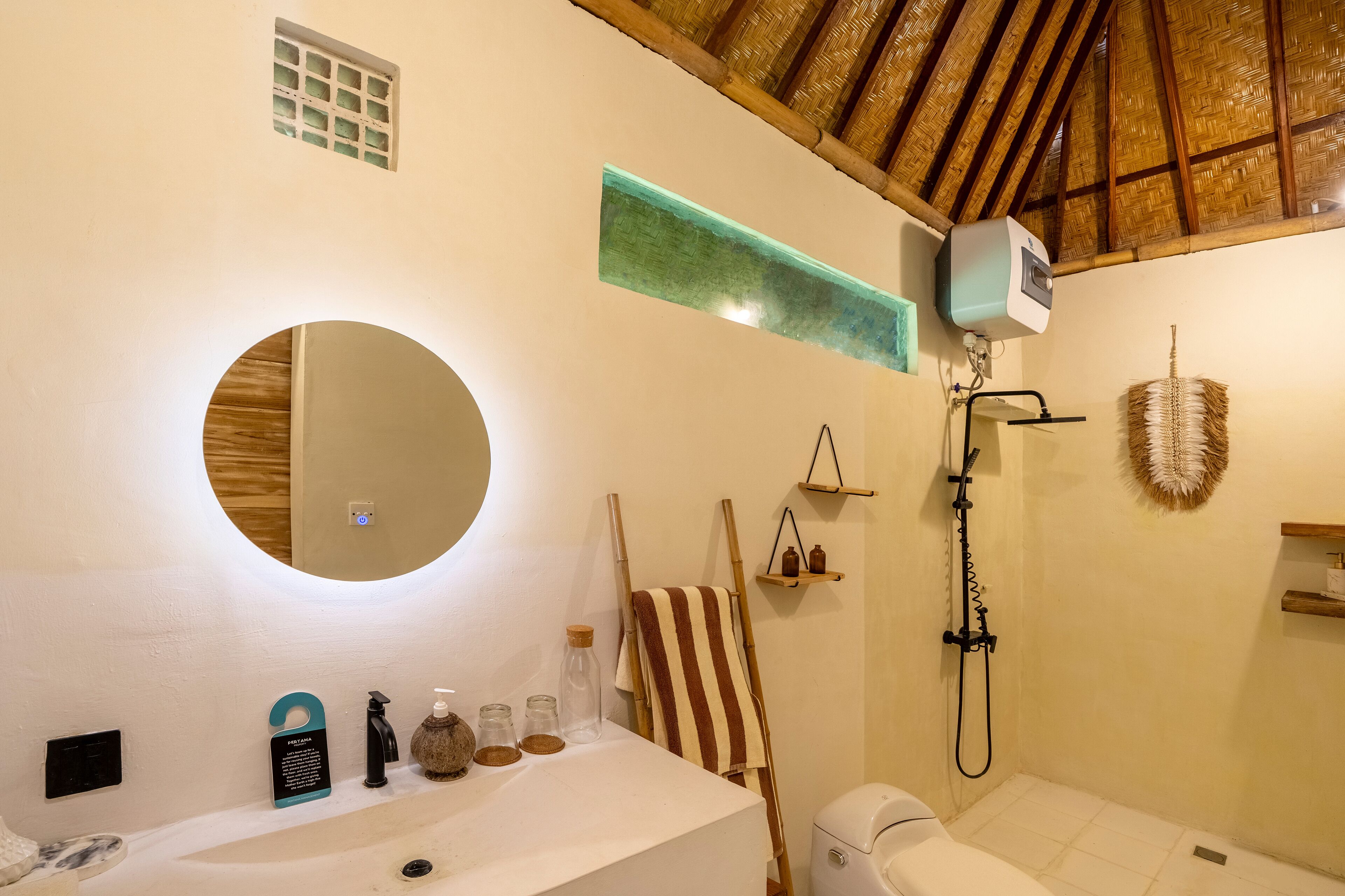 A bathroom with a round mirror, a towel rack, a shower, and a sink.