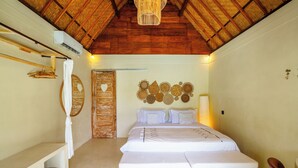 Ein Schlafzimmer mit Holzbalkendecke, einem Bett mit weißer Bettwäsche, einem Nachttisch, einem Spiegel und einer Wanddekoration.