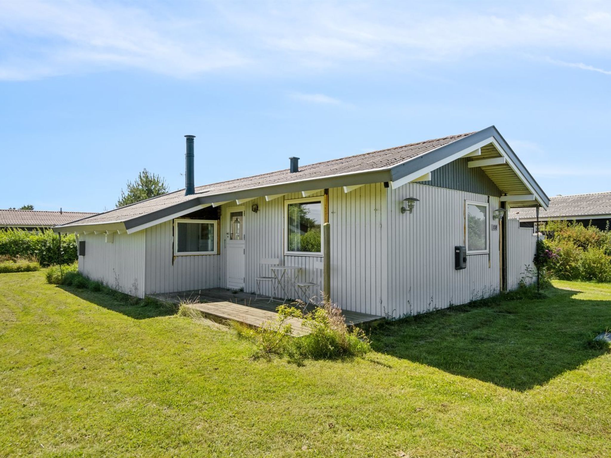 Et etplanshus med saddeltag, en veranda og en skorsten.