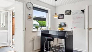 A modern kitchen with a black countertop, two bar stools, a hanging pendant light, and a whiteboard with motivational writing.
