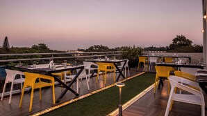 An outdoor dining area with tables and chairs, a pool, and a view of the surrounding landscape. - Hotel Urban Jade (Bengaluru)